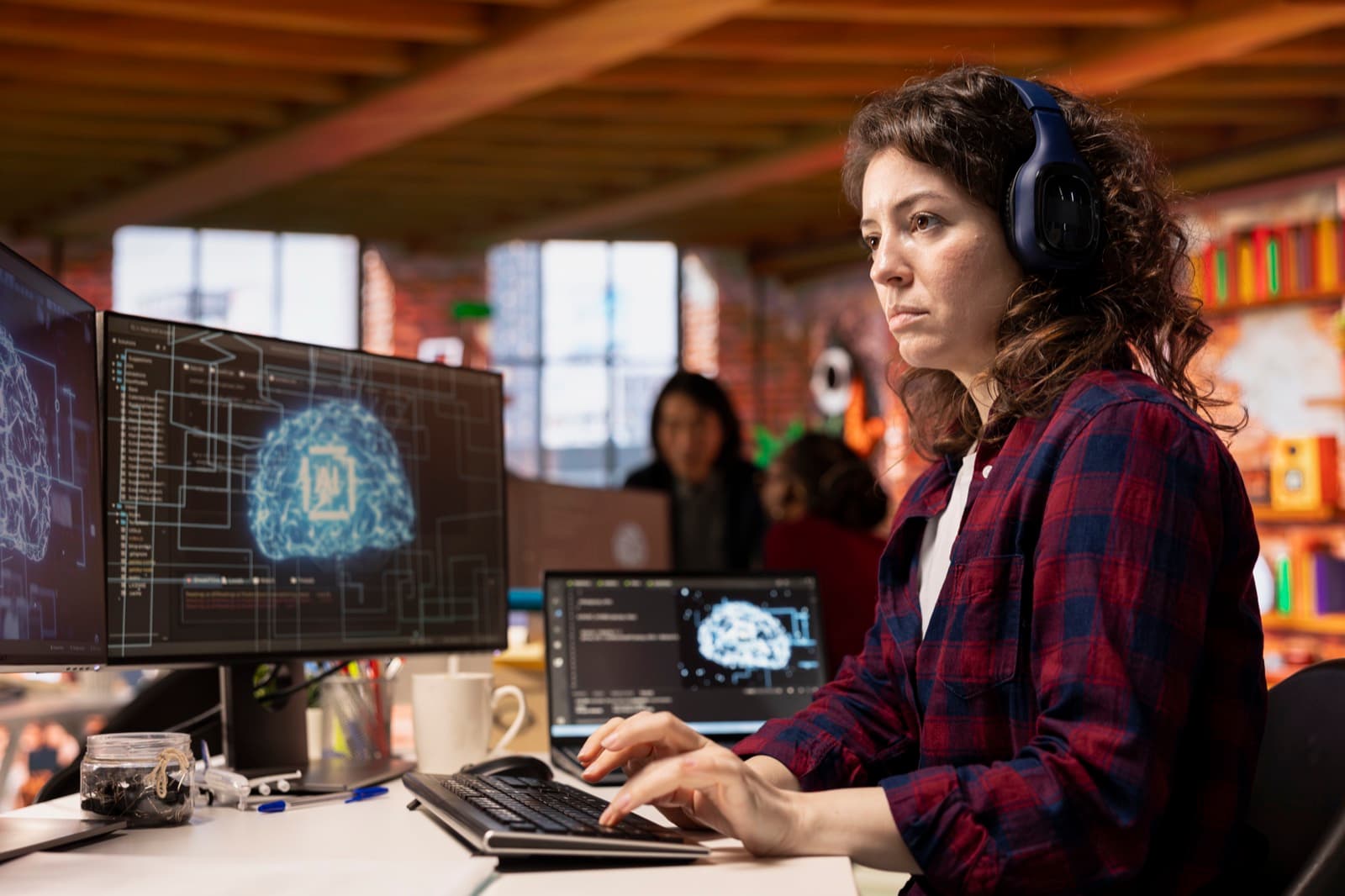 IT specialist with headphones using artificial intelligence tools across multiple monitors